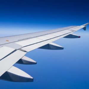 Flight Booking Service Pass product image: airplane wing above clouds with blue sky, clean copy space