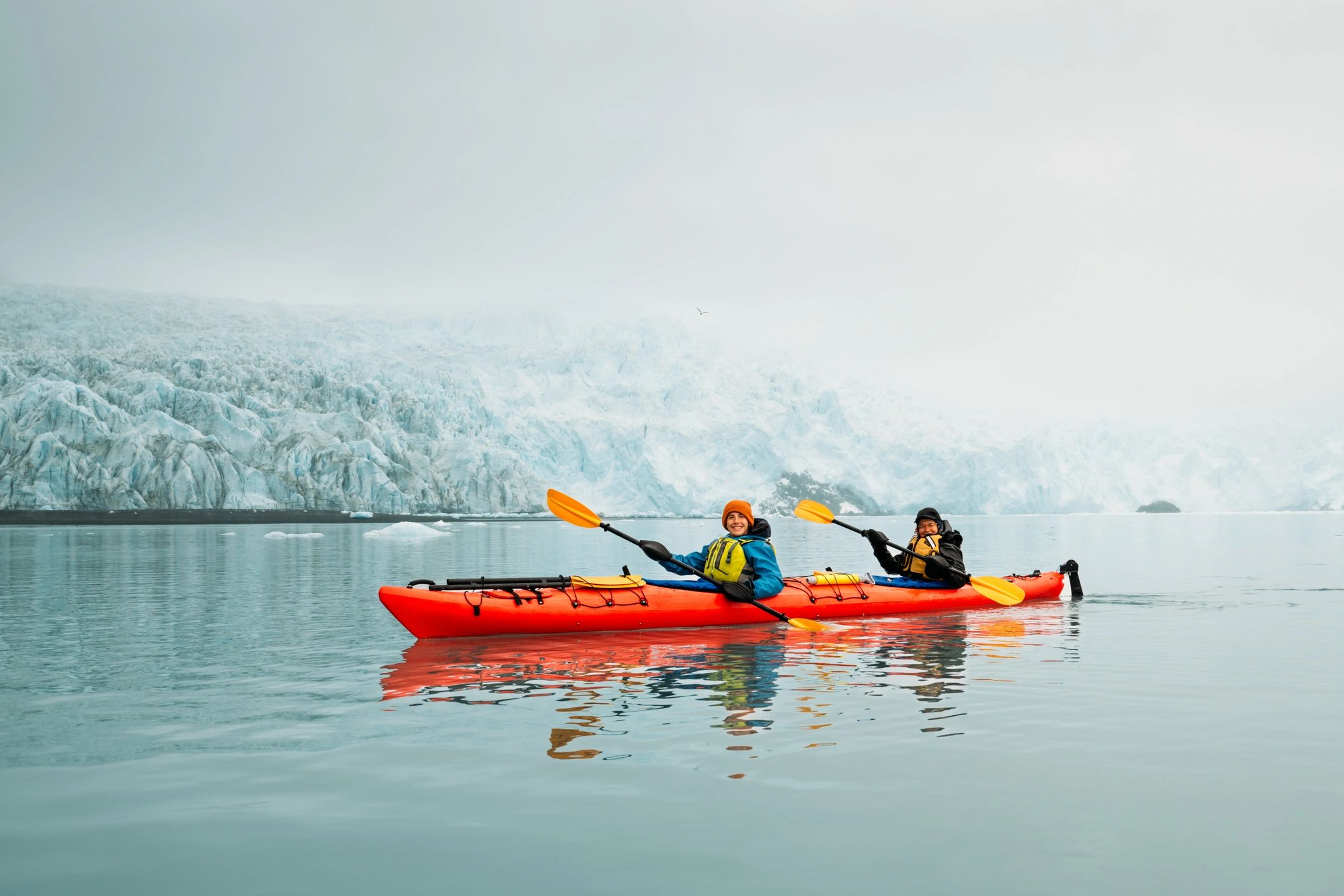 Mother and son kayaking toward a glacier in Alaska